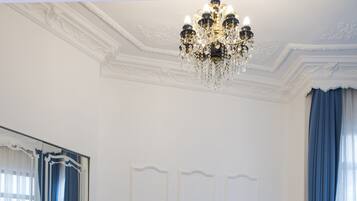 Una habitación de hotel con una cama grande, un candelabro, una mesita de noche y un espejo.