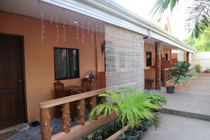 A house with a wooden porch, a dining area with chairs and a table, and potted plants. - Golden Sam Resort (Panglao)
