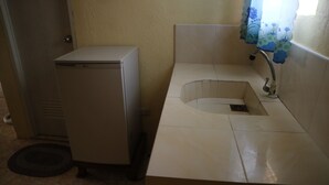 Ein kleines Badezimmer mit Waschbecken, Toilette und kleinem Kühlschrank.