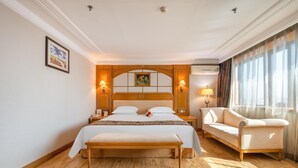 A hotel room with a large bed, a bench, a sofa, and a nightstand with a lamp. - Hotel Silverland (Dongguan)