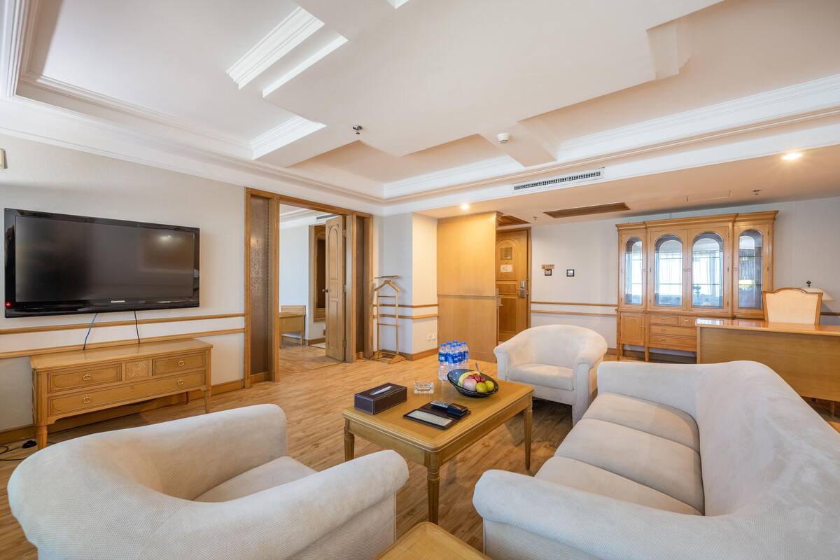 Un salón espacioso con un televisor de pantalla plana, un mueble de madera y un comedor con mesa y sillas.