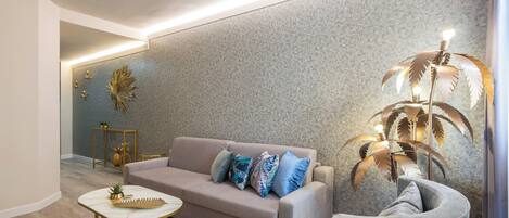 A modern living room with a sofa, armchair, and decorative plant.