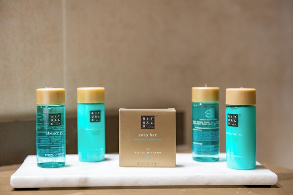 Un estante de baño con cinco productos de cuidado corporal de Rituals, incluyendo una pastilla de jabón y acondicionador.