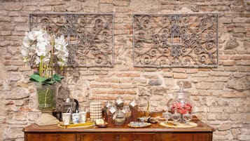 Une table de buffet en bois, ornée de divers plats et décorations, est placée contre un mur de briques.