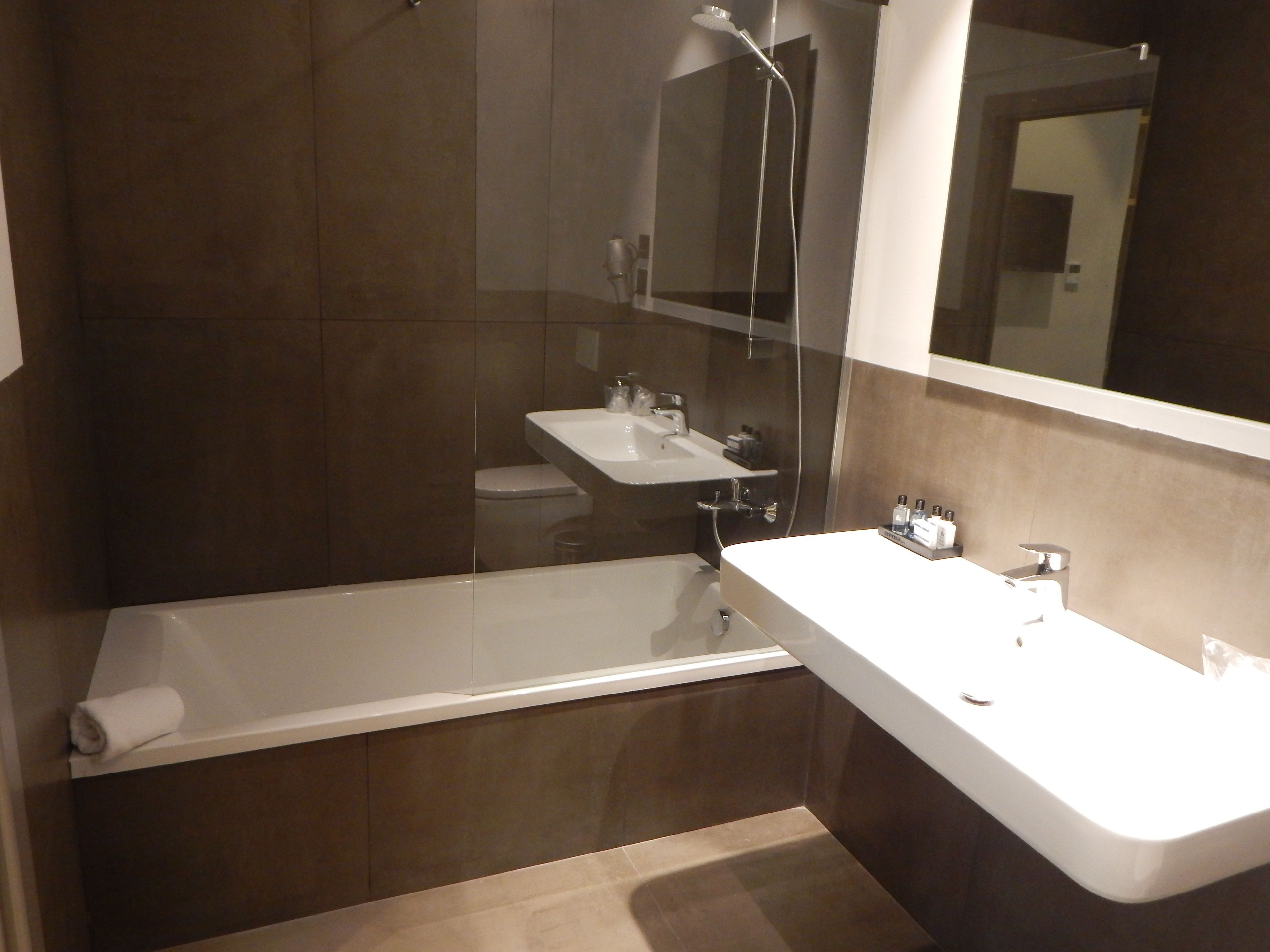 Une salle de bain moderne dotée d’une douche à parois de verre, d’une baignoire sur pieds et d’un meuble-lavabo avec un miroir.