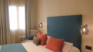 Een hotelkamer met een groot bed, een stoel en twee wandlampen.