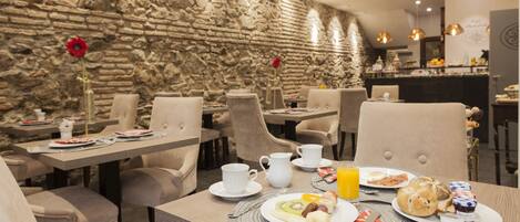 Mesa de desayuno con sillas y pared de piedra.