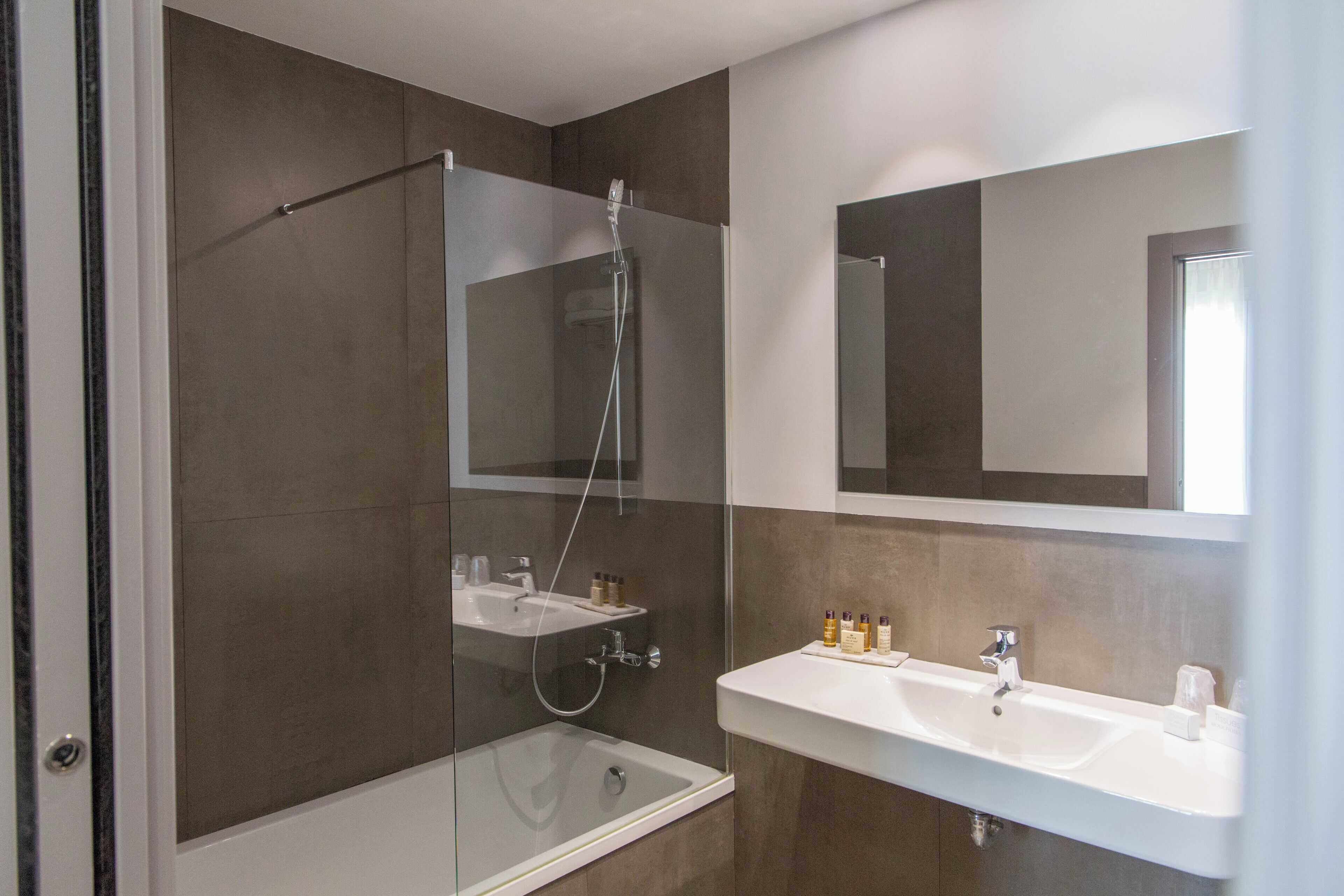 A modern bathroom with a glass-enclosed shower, a bathtub, and a vanity with a mirror.