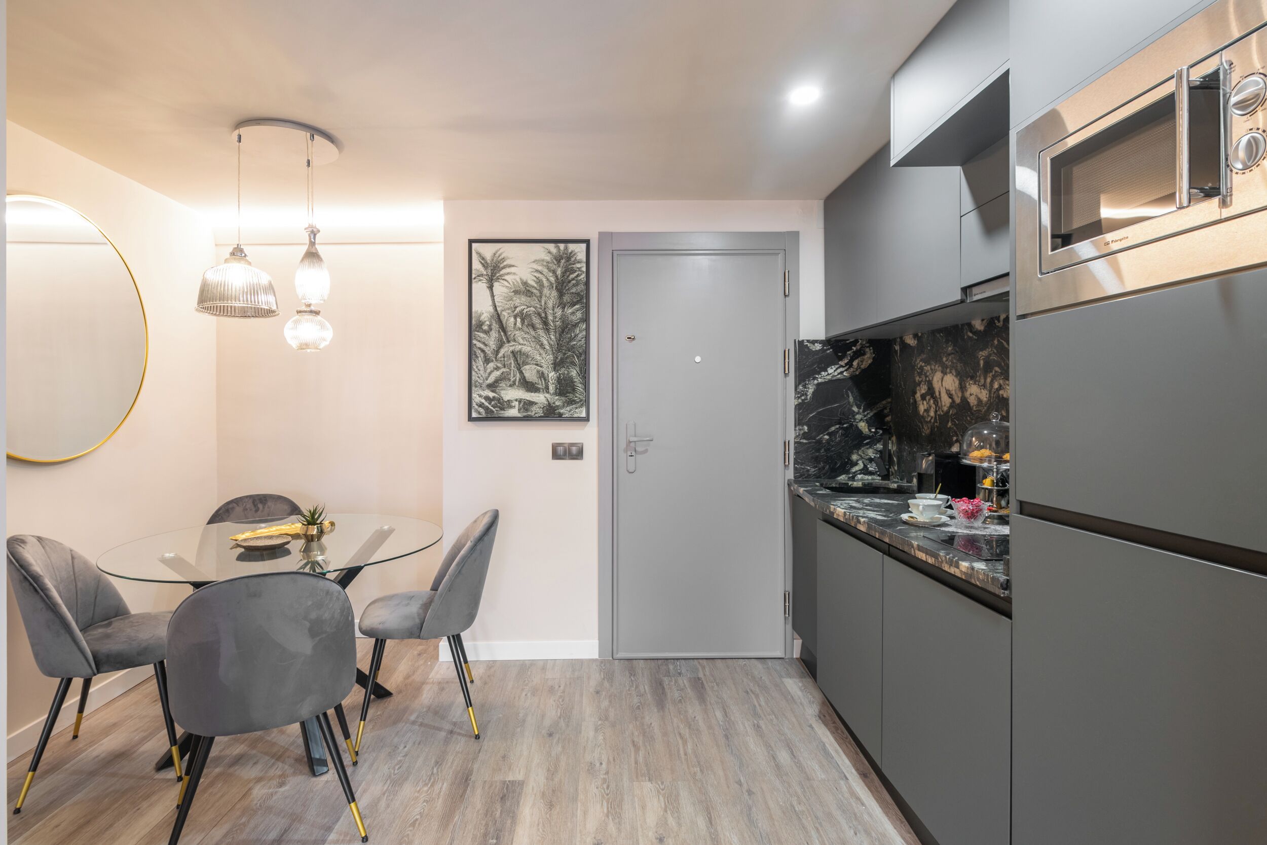 A modern kitchen with grey cabinets, a built-in oven, and a marble countertop.