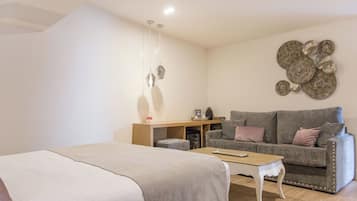 A bedroom with a bed, a desk, a sofa, and a coffee table.