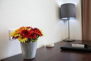 A desk with a metal vase containing colorful flowers, a lamp, and a notebook. - Shanghai Coinfamily Hotel (Shanghai)
