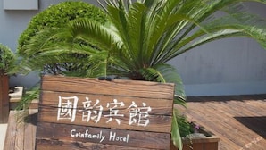 Ein Holzschild für das Coinfamily Hotel mit chinesischen Schriftzeichen und englischem Text.