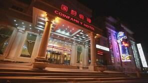 The exterior of the CoinFamily Hotel with a grand entrance, large columns, and illuminated signage. - Shanghai Coinfamily Hotel (Shanghai)