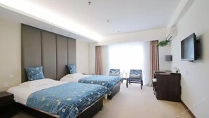 Ein Hotelzimmer mit zwei Betten, einem Fernseher, einem Schreibtisch und Blick ins Freie.
