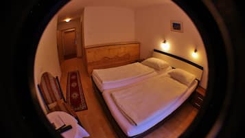 Ein Rundblick auf ein Hotelzimmer mit einem hölzernen Kopfteil, zwei Betten, einem Nachttisch, einem Sessel und einem kleinen Teppich.