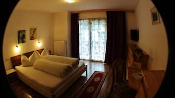 Ein Schlafzimmer mit einem Bett, einem Holztisch, einem Stuhl, einer Heizung und einem Fenster mit Vorhängen.