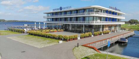 Un hotel moderno con fachada de vidrio, un muelle y vistas al agua.