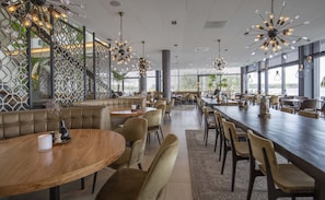 A modern restaurant with high ceilings, exposed beams, and a mix of booth and table seating. - Fletcher Hotel Het Veerse Meer (Arnemuiden)