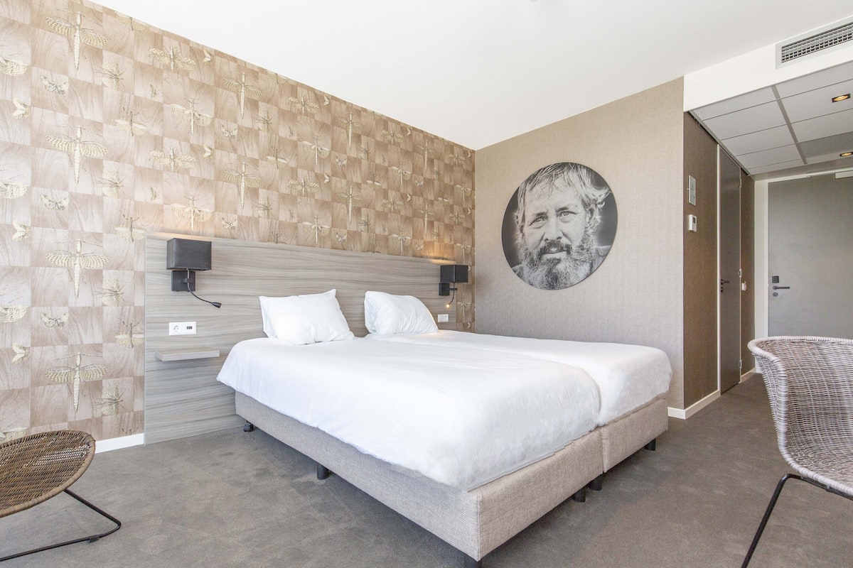 Ein modernes Hotelzimmer mit einem großen Bett, einem an der Wand befestigten Fernseher und einem einzigartigen, gemusterten Wandpapier.
