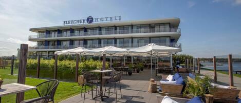 A hotel with outdoor seating and a view of the water.
