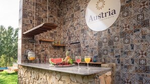 Una barra de piedra con salpicadero de azulejos, frutas y bebidas, y un cartel de Austria Luxury Apartments.