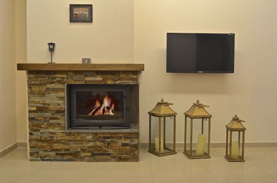 Una chimenea de piedra con un televisor montado encima, y tres faroles a un lado.