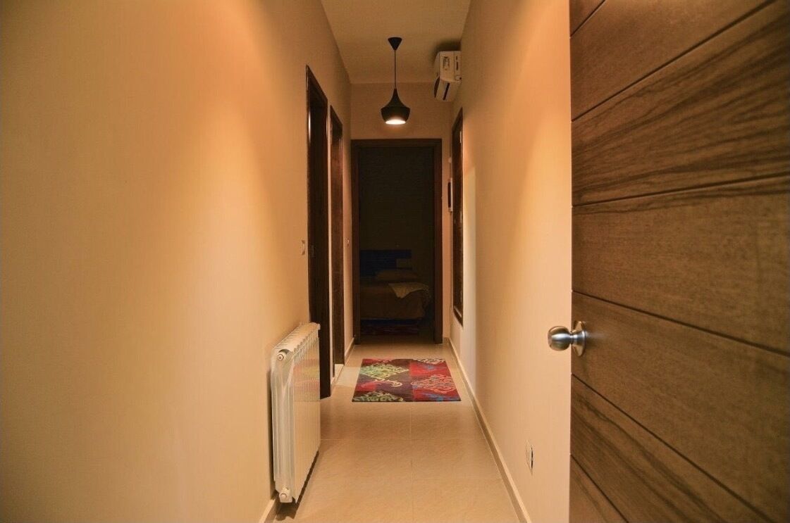 A narrow hallway with a radiator on the left, a door on the right, and a ceiling light.