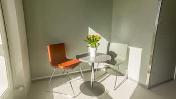 Una habitación moderna con una mesa redonda, una silla naranja y una planta en maceta.