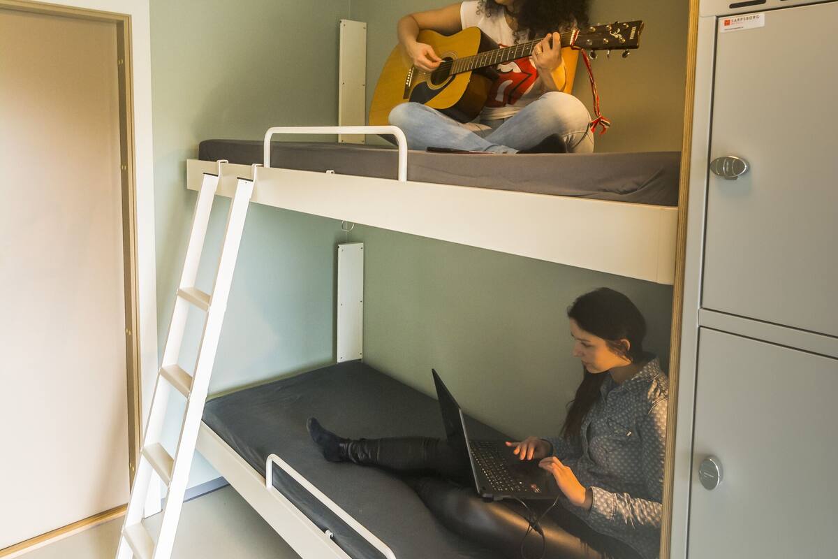 Ein Schlafzimmer mit Etagenbetten, einer Gitarre und einem Laptop auf dem unteren Bett.