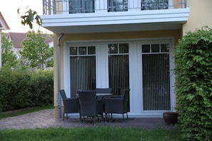 Un patio con una mesa, sillas, una planta en maceta y un edificio con balcón.
