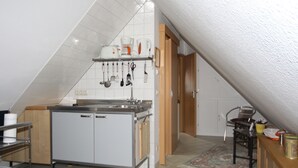 A kitchen with a central island, a sink, and a stove. There are hanging utensils above the island.