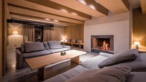 Een moderne woonkamer met een open haard, houten balken in het plafond en een gezellige zithoek.