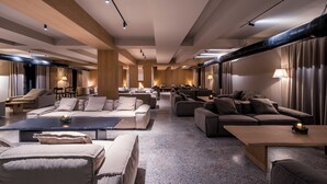 Een ruime hotellobby met diverse zithoeken, waaronder banken en fauteuils, geplaatst rondom een centrale salontafel.