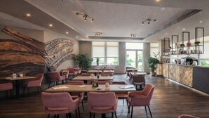 A spacious restaurant with high ceilings, modern lighting, and a large wooden wall feature. Tables are arranged for dining, and there is a bar area with shelves. - Lázeňský Hotel Pyramida I (Frantiskovy Lazne)