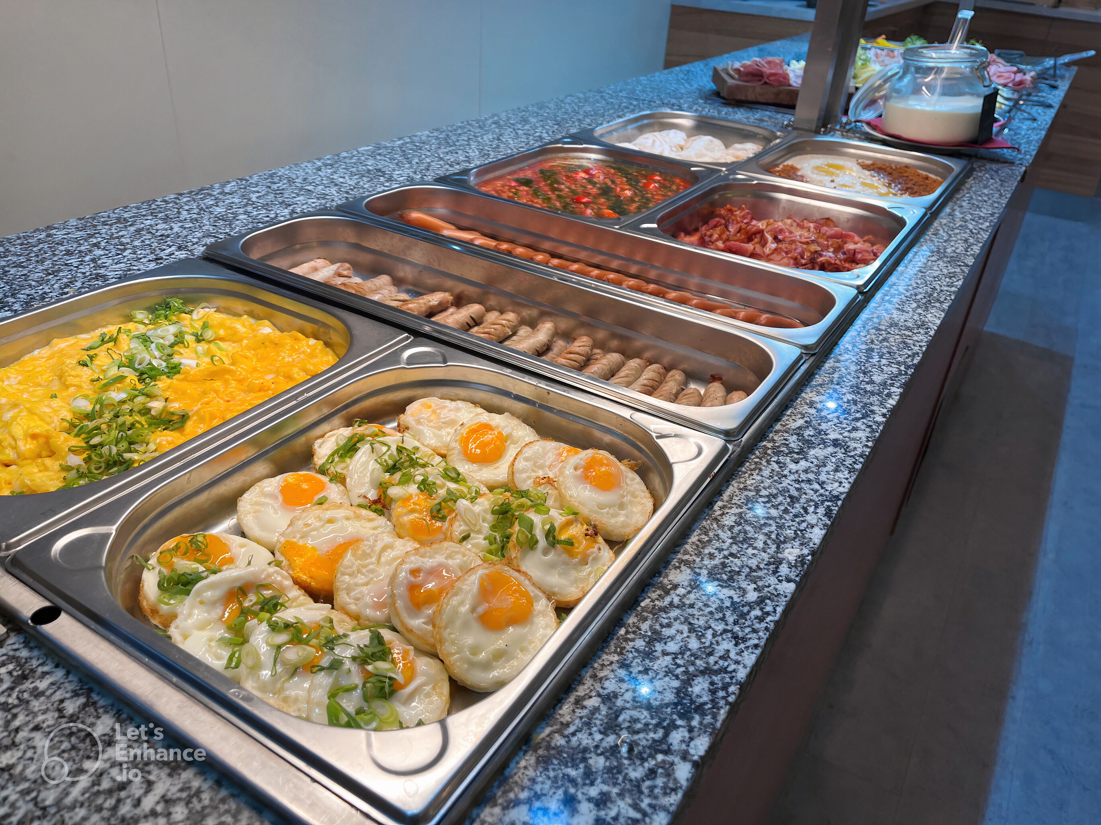 A buffet with various food options including eggs, sausages, and other dishes.