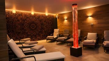 Un cuarto de spa con sillones reclinables, un muro decorativo y una fuente central.