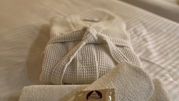 Cama bem arrumada com toalha e um pequeno objeto sobre ela.