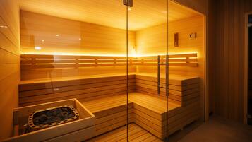 A sauna with wooden benches, glass walls, and a stone basin.