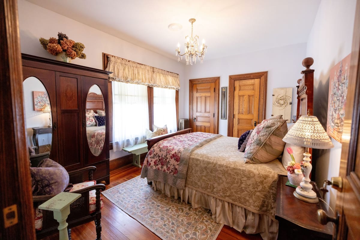A bedroom with a bed, dresser, vanity, and a chandelier.