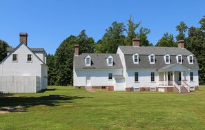 A large white house with a front porch and multiple chimneys, surrounded by a grassy field and trees. - Gracefield Hall B&B (Providence Forge)