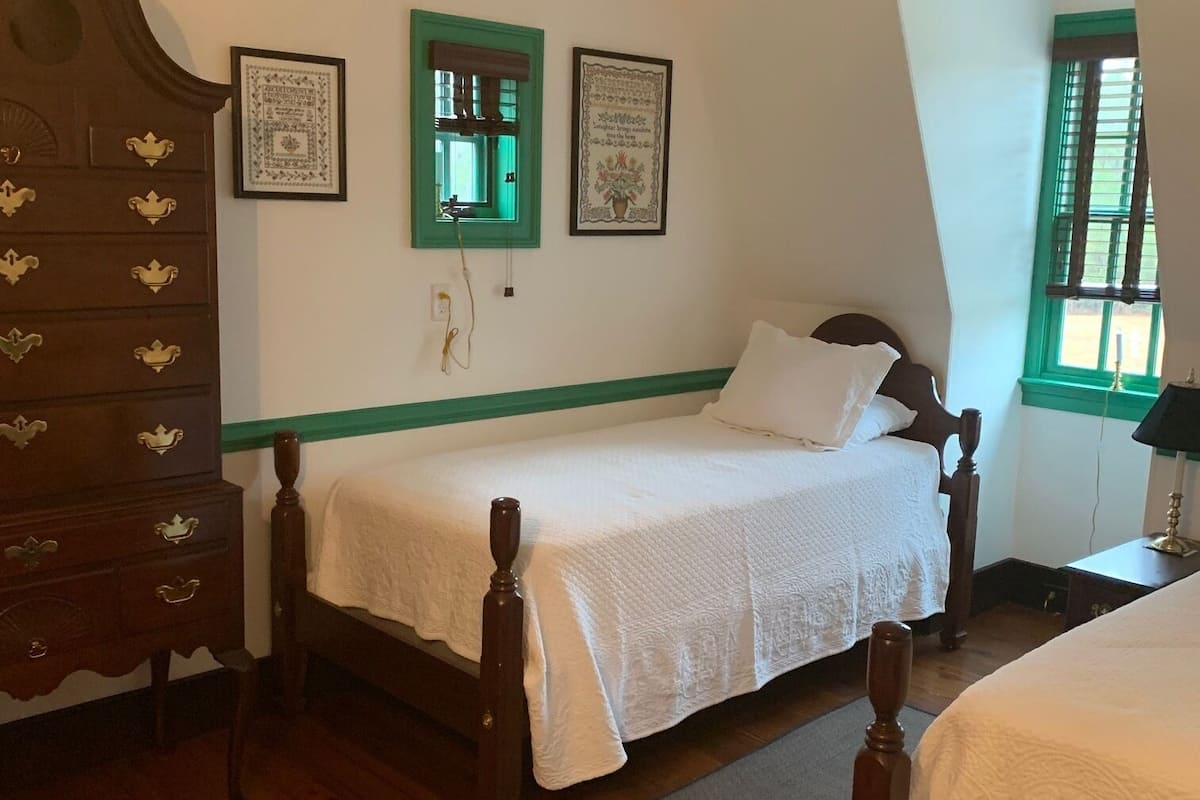 A room with a wooden bed, a dresser, and two framed pictures on the wall.