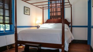 A four-poster bed with a wooden frame, a bedside table with a lamp, and a picture on the wall.
