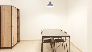 A room with a wooden cabinet, a table with chairs, and a hanging light fixture. - Colosseo Friendly Suite & Rooms (Rome)