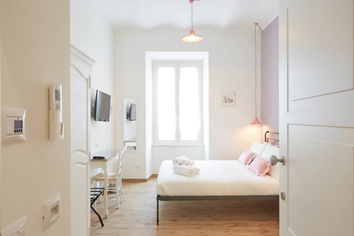 A bedroom with a bed, bedside table, and a window.