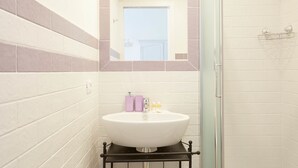 A bathroom with a white sink, a mirror, and a shower area. - Colosseo Friendly Suite & Rooms (Rome)