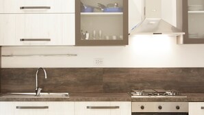 A modern kitchen with white cabinets, a stainless steel sink, a gas stove, and a built-in microwave. - Colosseo Friendly Suite & Rooms (Rome)