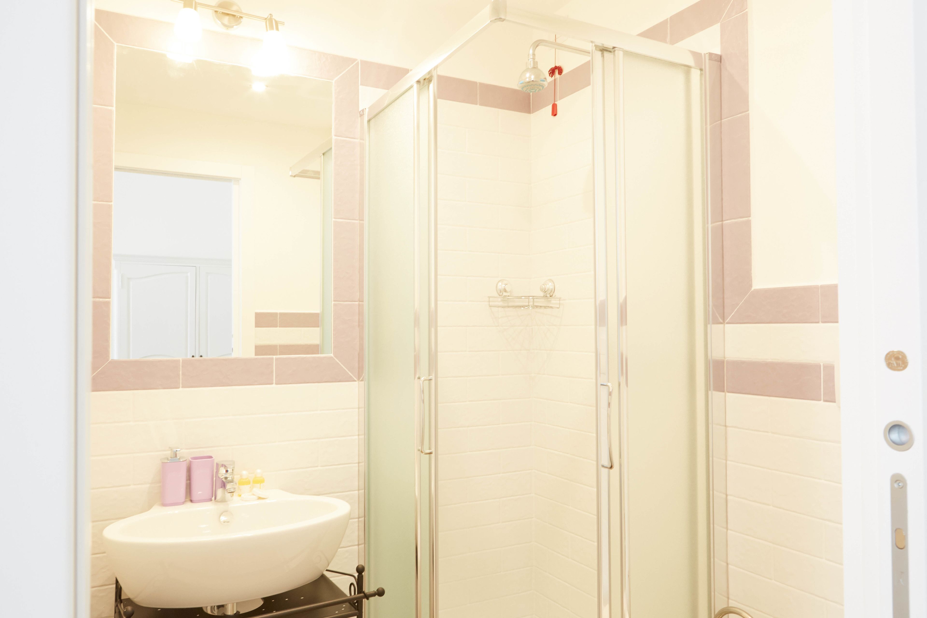 A bathroom with a white sink, a glass shower enclosure, and a mirror above the sink.