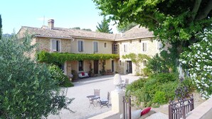 A stone building with a courtyard, outdoor seating, and a gate.