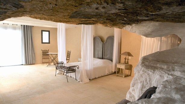 A bedroom with a bed, a chair, a table, and a lamp.