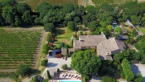 An aerial view of a property with a swimming pool, multiple buildings, and surrounding vineyards.